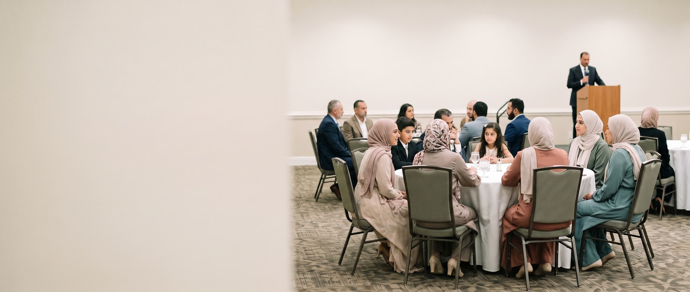 Families and friends at a community gala dinner, women and men at their own tables